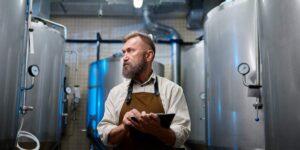 brewery worker employee checking tanks with clipboard