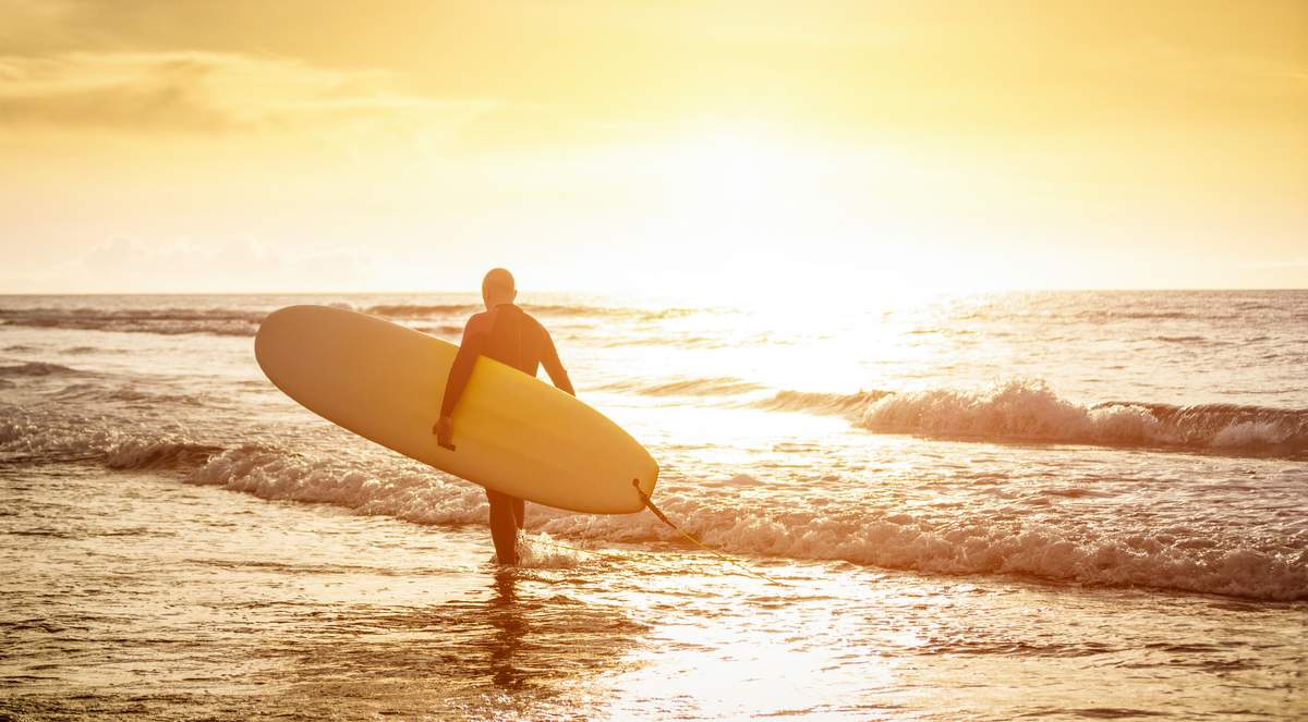 surfer walking on beach sunset water ocean